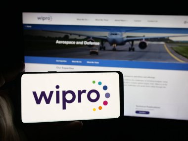 Stuttgart, Almanya - 09-29-2025: Hint teknoloji şirketi Wipro Limited 'in logosuna sahip akıllı telefon sahibi kişi web sitesinin önünde ekranda. Telefon ekranına odaklan.