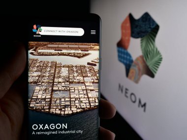 Stuttgart, Almanya - 09-29-2025: Suudi Arabistan gayrimenkul projesi NEOM 'un web sayfası olan akıllı telefonu logonun önünde tutan kişi. Telefon ekranının merkezine odaklan.