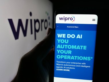 Stuttgart, Almanya - 09-29-2025: Hintli teknoloji şirketi Wipro Limited 'in internet sayfası ile logo önünde cep telefonu tutan kişi. Telefon ekranının merkezine odaklan.