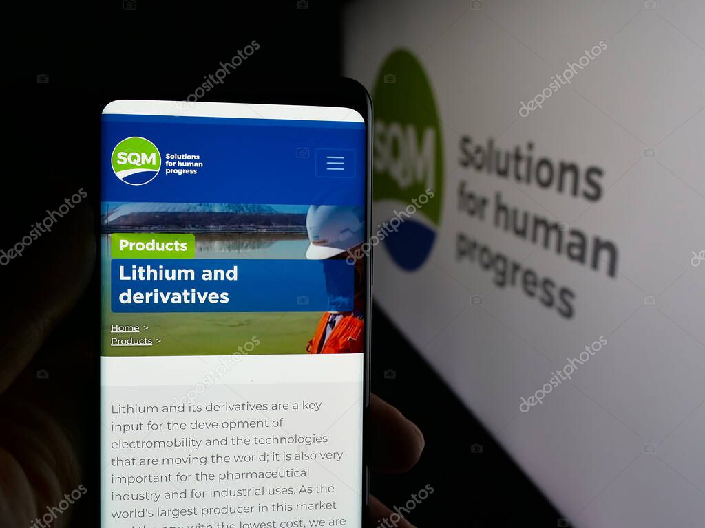 Stuttgart, Germany - 09-28-2025: Person holding smartphone with web page of Sociedad Quimica y Minera de Chile (SQM) on screen in front of logo. Focus on center of phone display.