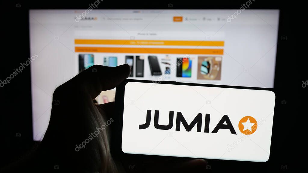 Stuttgart, Germany - 09-29-2025: Person holding mobile phone with logo of e-commerce company Jumia Technologies AG on screen in front of web page. Focus on phone display.
