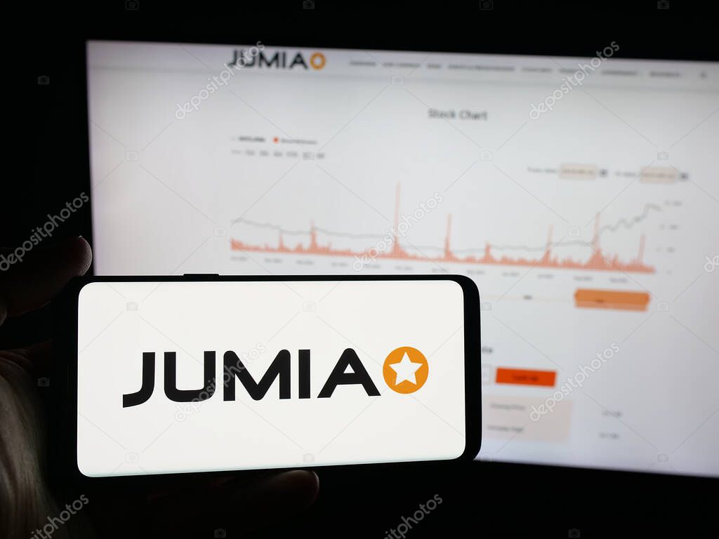 Stuttgart, Germany - 09-29-2025: Person holding smartphone with logo of e-commerce company Jumia Technologies AG on screen in front of website. Focus on phone display.