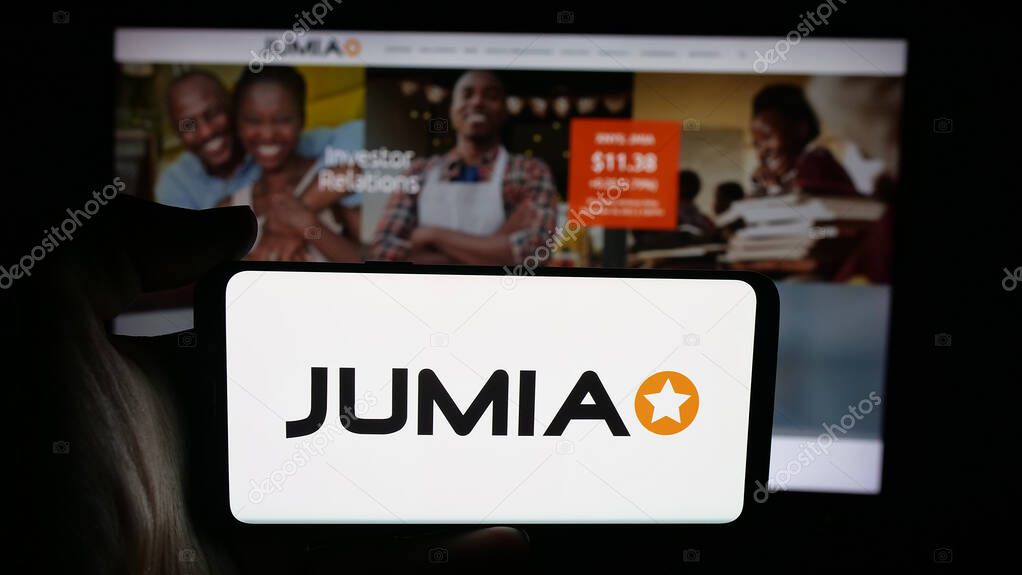 Stuttgart, Germany - 09-29-2025: Person holding cellphone with logo of e-commerce company Jumia Technologies AG on screen in front of webpage. Focus on phone display.