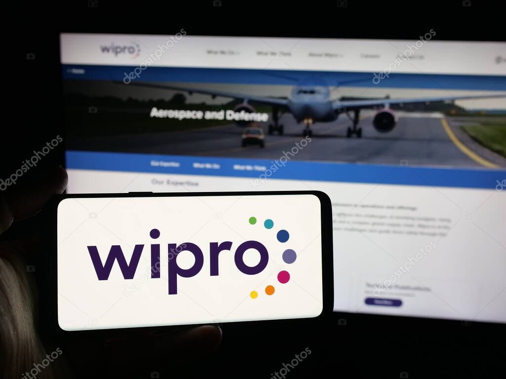 Stuttgart, Germany - 09-29-2025: Person holding smartphone with logo of Indian technology company Wipro Limited on screen in front of website. Focus on phone display.