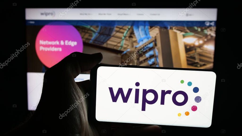 Stuttgart, Germany - 09-29-2025: Person holding mobile phone with logo of Indian technology company Wipro Limited on screen in front of web page. Focus on phone display.