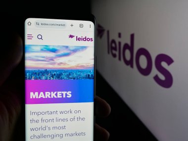 Stuttgart, Almanya - 10-01-2025: ABD 'li savunma şirketi Leidos Holding Inc.' in web sayfası ile akıllı telefon sahibi kişi logonun önünde ekranda. Telefon ekranının merkezine odaklan.