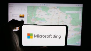 Stuttgart, Almanya - 10-01-2025: İnternet arama motoru logosu olan cep telefonu sahibi kişi Microsoft Bing web sayfasının önünde ekranda. Telefon ekranına odaklan.