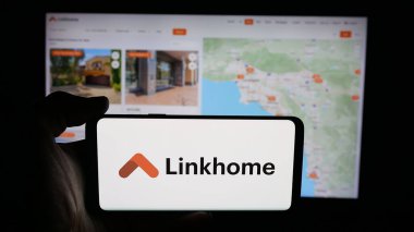 Stuttgart, Almanya - 10-04-2025: Web sayfası önünde ekranda ABD 'li emlak şirketi Linkhome Holding Inc.' in logosunun bulunduğu cep telefonu sahibi kişi. Telefon ekranına odaklan.