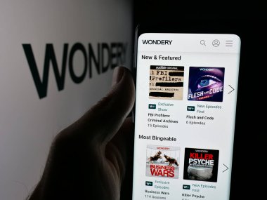 Stuttgart, Almanya - 10-04-2025: ABD Podcast ağı Wondery 'nin web sayfası olan akıllı telefon sahibi kişi logonun önünde ekranda. Telefon ekranının merkezine odaklan.