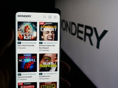Stuttgart, Almanya - 10-04-2025: ABD Podcast ağı Wondery 'nin web sayfası olan cep telefonu sahibi kişi logonun önünde ekranda. Telefon ekranının merkezine odaklan.