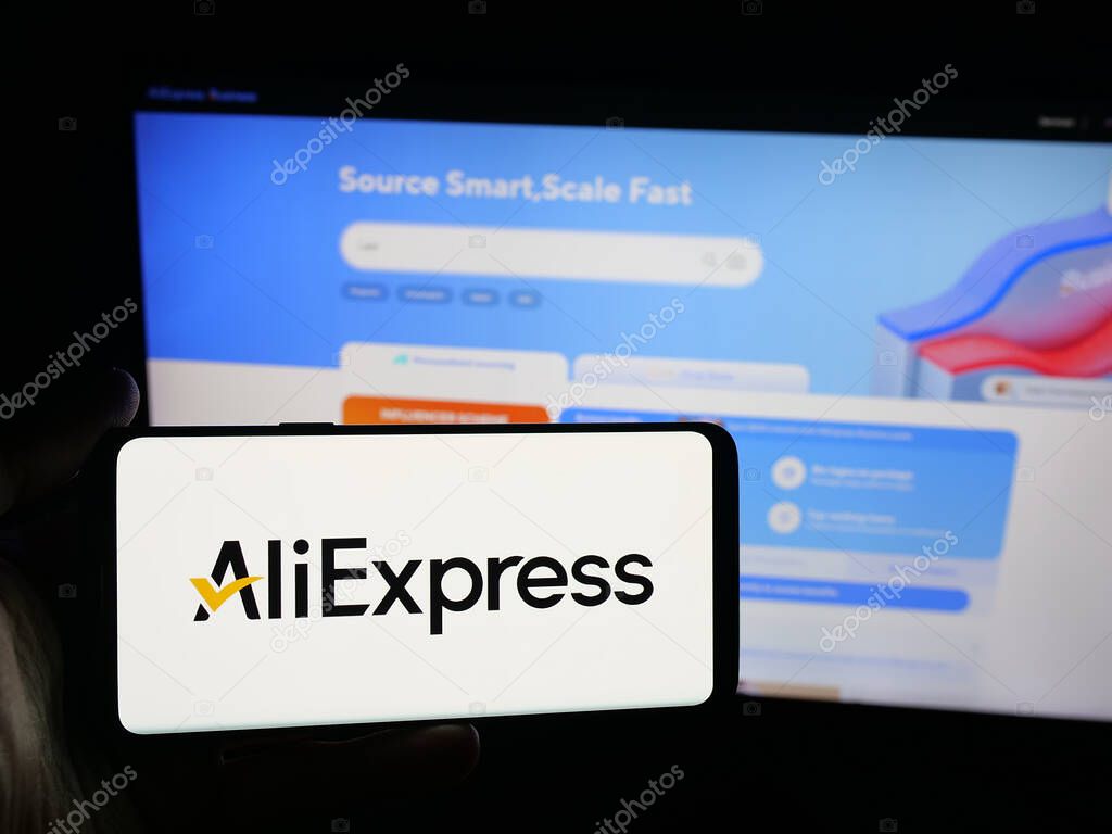 Stuttgart, Germany - 10-01-2025: Person holding smartphone with logo of Chinese e-commerce company AliExpress on screen in front of website. Focus on phone display.