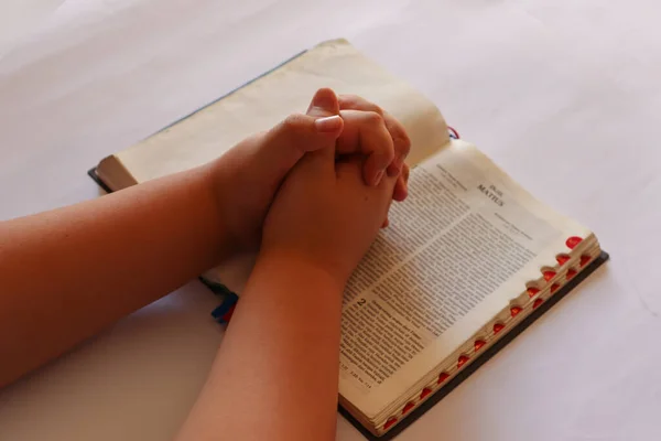 A Hand Praying on the Bible with White Background