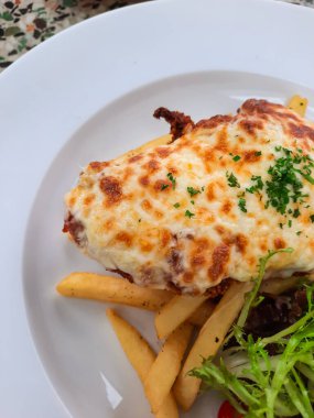 A Mozarella Cheese and Other Cheese Melted on a Chicken, Fries, and Salad on a White Plate