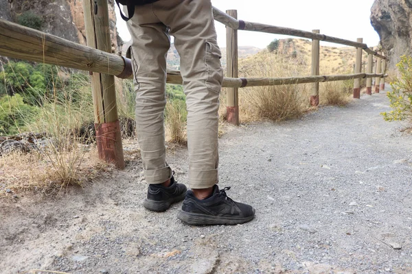 一个穿着长卡其裤和黑鞋的人准备在一条远足道上过桥 — 图库照片