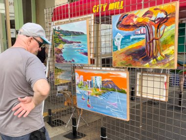 Honolulu, Hawaii, 8 Ekim 2022 - Çin Mahallesi Sanat Sergisi - Erkek müşteri satılık resimlere bakar.