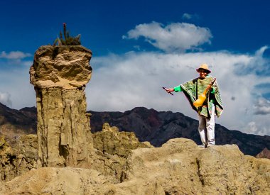 Moon Valley, Bolivya, 01162023 - İnsan kaya tepesinde dururken ev yapımı flüt çalar.