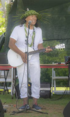 Honolulu, Hawaii, ABD - 2022-08-20 - Shaka Filming Hukilau - Yerel müzisyen açık hava sahnesinde gitar çalıp şarkı söylüyor.