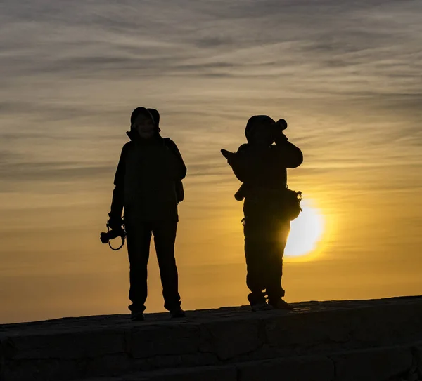 Silhouette of people at sunrise on a mountain top.
