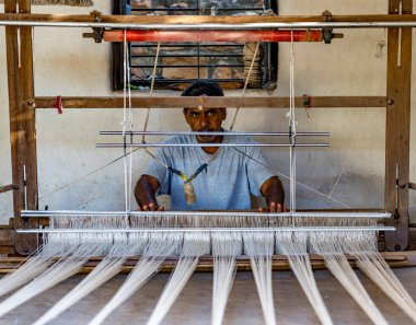 Odaklanmış zanaatkar bir dokuma tezgahı üzerinde çalışarak, ustalıkla tekstil yaratıyor.
