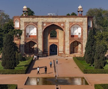 Turistler şafak vakti kemerli ve kubbeli antik bir Babür anıtını keşfediyorlar.