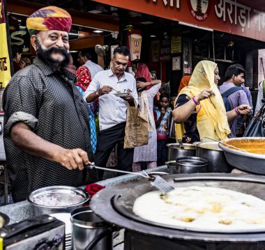 Hintli şef kalabalık bir market tezgahında geleneksel yemek hazırlıyor.