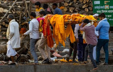 Grup, Hindu cenaze ayinlerinin bir parçası olarak Varanasi 'nin ghatlarında yakılmak üzere bir ceset taşıyor.