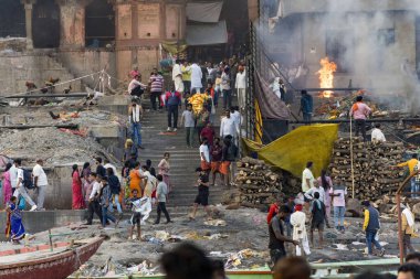 Hindistan, Varanasi 'deki kutsal nehir çeteleri boyunca geleneksel bir Hindu cenaze odununun hareketli atmosferini gösteren fotoğraf.