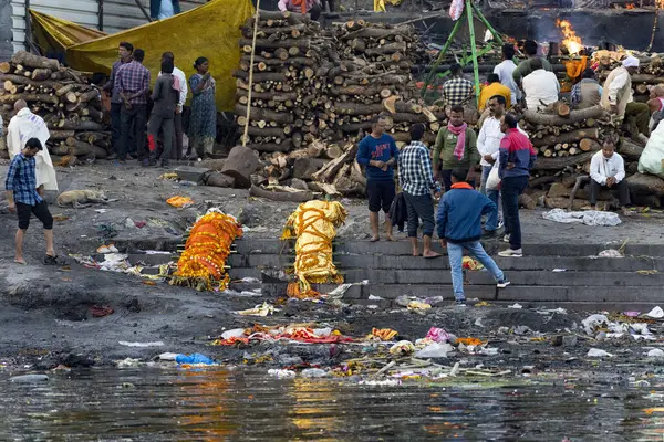 stock image Group of people partaking in traditional funeral rites by the river, with pyres and offerings