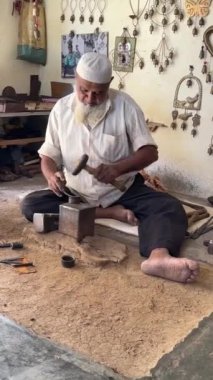 Geleneksel atölyede el yapımı metal işçiliği ile bakır ev çanları yapmada usta bir zanaatkar.