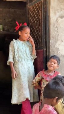 Yerel çocuklar, Hindistan 'ın kırsal bir köyünde geleneksel bir evin yakınında kültür ve gelenekleri sergileyerek şarkı söyleyip dans ediyorlar.