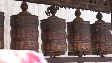 Nepal, Kathmandu 'daki bir Budist tapınağında dua çarkları dönüyor. Sembolik yazıtlı bakır tekerlekler