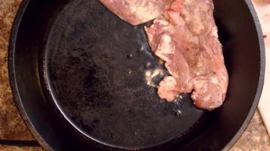 Şef baharatlı tavşan parçalarını kızgın demir bir tavaya yerleştirir ve lezzetli bir yemek yapmak için kızartırlar.