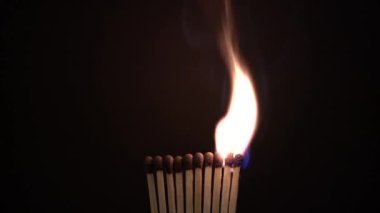 Sıra sıra yanan kibritler siyah arka planda, büyüleyici ateş ve ışık dansını sergiliyor