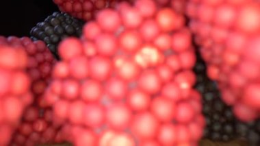 Kameranın geri çekilmesi, ahşap bir yüzey üzerinde duran canlı kırmızı ve siyah jelibon yığınını gösteriyor.