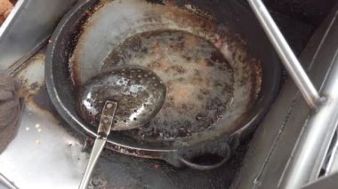 Sokak yemekleri sergileniyor. Bir şef, metal elek kullanarak kabarcıklı tavadan çıtır çıtır pakora topluyor.