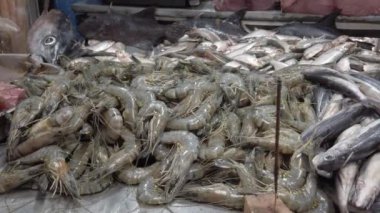 Balıkçıların tezgahında taze karidesler var. Sinekleri uzak tutmak için tütsü çubuğu yanıyor.