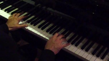 Büyüleyici bir konser performansı sırasında siyah bir piyanonun anahtarlarını ustalıkla çalan elleri kapat
