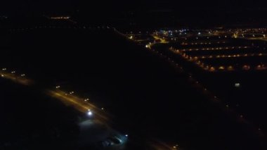 Gece vakti ışıl ışıl parlayan bir piste inen uçak, aşağıdaki canlı şehir ışıklarını ve kentsel manzarayı gözler önüne seriyor.