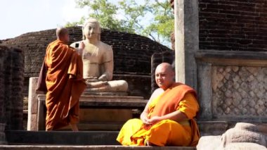 Budist rahipler Polonnaruwa, Sri Lanka 'da Buda heykeliyle poz verirken eğleniyorlar.