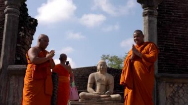 Budist keşiş, Polonnaruwa, Sri Lanka 'da tarihi bir Buda heykelinin yanında bir turistle fotoğraf çektirmek için poz veriyor.