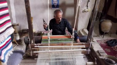 İsfahan, İran 'da deneyimli bir zanaatkar ahşap dokuma tezgahında titizlikle geleneksel bir aliaqa pelerini örüyor.