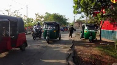Yaşlı adam Nogombo, Sri Lanka 'da işlek bir yolda yürüyor, düz olmayan kaldırımda yürüyor ve trafiği geçiyor.