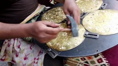 Esnaf, Mısır 'da, Kahire' de pirinç bir plakaya çiçek deseni kazımak için çekiç ve keski kullanıyor.