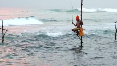 Galle, Sri Lanka 'da dengede duran balıkçı, pitoresk bir günbatımında okyanusta balık yakalar.