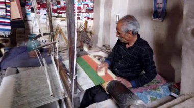 Yaşlı bir zanaatkar İsfahan, İran 'daki atölyesinde geleneksel bir pelerin dokuyor.