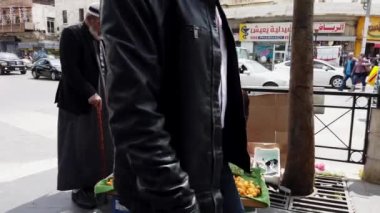 Kayısı satıcısı Amman, Jordan 'da bir kaldırımda bekliyor, güneşin altında canlı bir şehir batımında müşteri arıyor.