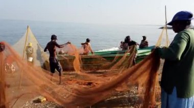 Sahilde işbirliği yapan balıkçılar ağları çeker ve küçük balıkları okyanusa geri salarlar.