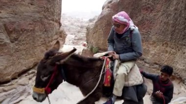 Eşeğe binen turistler, Petra, Ürdün 'de muhteşem kumtaşı uçurumlarıyla çevrili dar bir vadi olan Siq' te geziniyorlar.