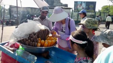 Aile üyeleri, Sri Lanka 'daki bir sokak yemeği tedarikçisinden koçandaki taze mısırları seçerek, canlı bir yerel deneyimin tadını çıkarıyorlar.