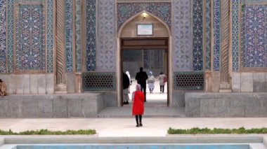 Kırmızı paltolu kadın Kerman 'daki Ganjali camisine giriyor. Bir grup molla da oradan ayrılıyor.